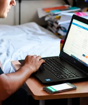 Молодой человек работает на ноутбуке за столом